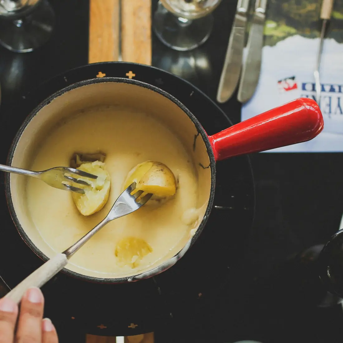 Caquelon de fondue sur son réchaud, deux fourchettes plongées dans le fromage